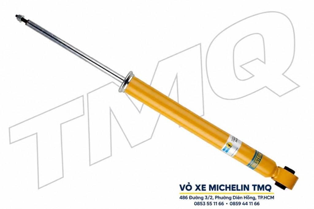 Phuộc Bilstein B6 sau màu vàng với đầu bắt dạng mắt và watermark TMQ